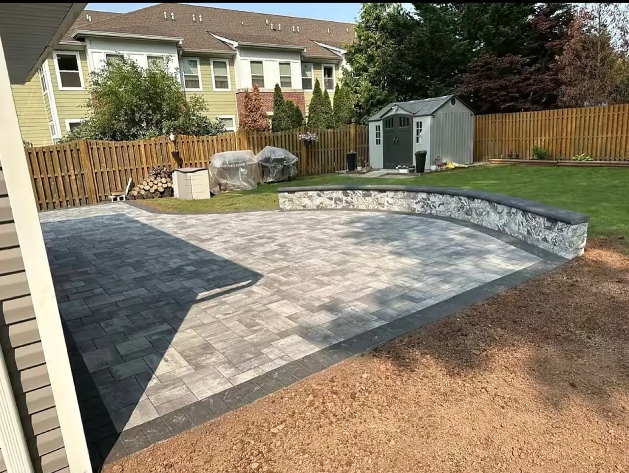 Finished backyard paver patio with stacked-stone seat wall